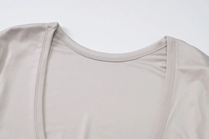 Dettaglio del collo a girocollo con doppia cucitura su top in maglia beige di alta qualità