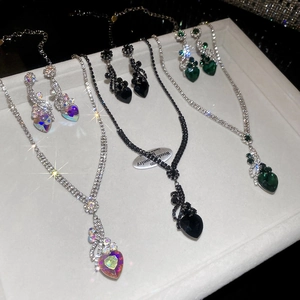 Detailed view of three heart-shaped jewelry sets with colorful, black, and green rhinestones