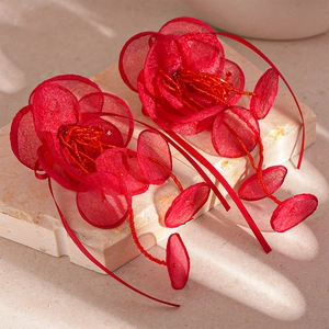 Boucles d'oreilles fleurs en tulle rouge avec pompons perlés sur fond de pierre