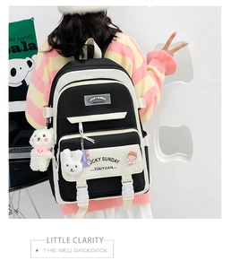 Detailed view of school backpack with plush bear charms and cute badges on layered pockets