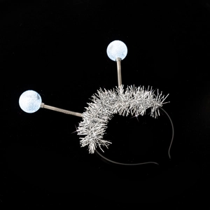 Close-up of sparkling silver tassels and blue pom-pom balls on a black party headband