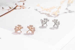 Macro detail of rose gold and silver tree branch earrings with sparkling crystal accents