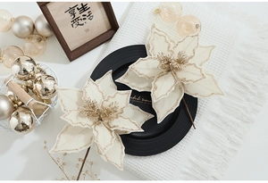 Close-up of two cream velvet poinsettia flowers with gold glitter edges and brown stems