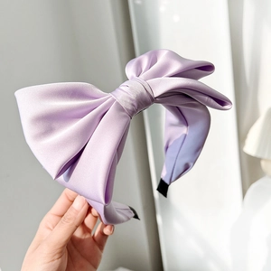 Detailed texture of lavender satin bow headband showing smooth fabric and elegant craftsmanship