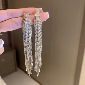 Macro detail of long gold tassel earrings with shimmering white cubic zirconia crystals