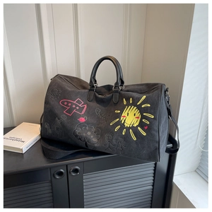 Close-up of a black travel bag with colorful cartoon graffiti and detachable shoulder strap