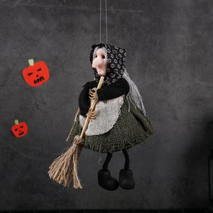 Hanging Halloween witch doll decoration with green dress and broom on grey background