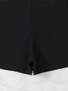 Detailed close-up of double-stitched reinforced seams on black tankini swim shorts