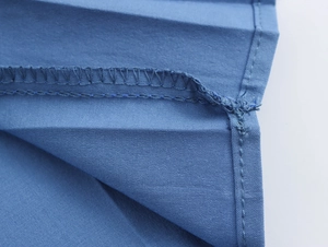 Detailaufnahme der präzisen Nähte und der blauen Tweed-Stofftextur des Kleides