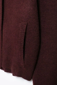 Gros plan de la poche et du tissu en laine sur le cardigan bordeaux à fermeture éclair