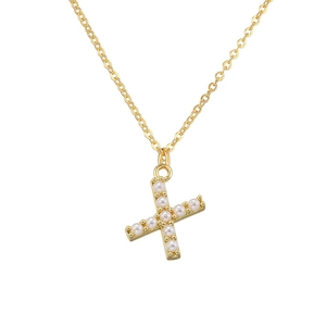 Macro shot of gold letter X pendant featuring small white pearls on a delicate chain