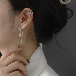Detail of silver tassel chain earrings with shimmering cubic zirconia on model's ear