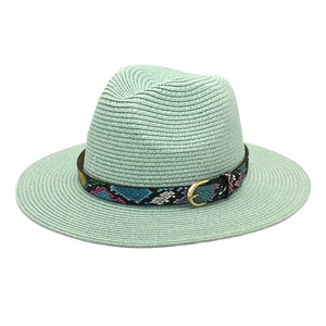 Close-up of woven straw fedora hat texture with colorful patterned ribbon and gold buckle