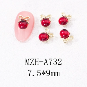 Détail des breloques à ongles avec perle rouge et nœud doré, dimension de 7.5x9mm