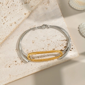 Zweifarbiger geometrischer Armreif in Gold und Silber auf Naturstein mit Muscheln