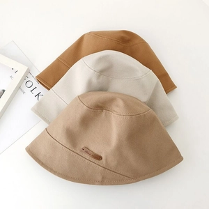 Detailed view of three cotton bucket hats with leather 'Hand Made' label in earth tones
