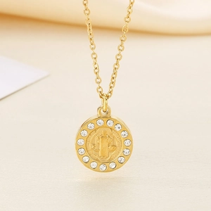 Nahaufnahme einer goldenen Münzhalskette mit Heiligenporträt und klaren Kristallen