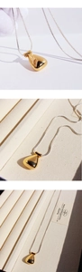Macro detail of a sleek gold teardrop pendant on a polished silver snake chain necklace