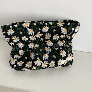 Close-up of daisy embroidery on a black canvas pouch with high-quality zipper and fabric label