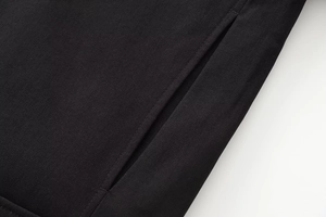 Close-up of black twill fabric texture and stitch detail on a short bomber jacket