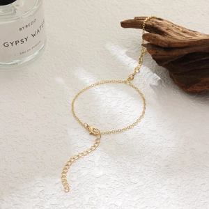 Golden delicate chain anklet with lobster clasp and extension on a rustic wooden background