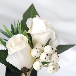 Elegant white rose boutonniere with green leaves and berries for wedding grooms