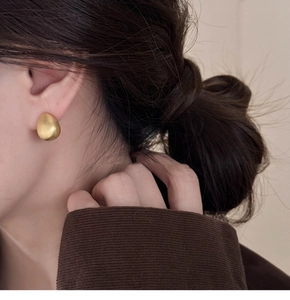 Detail of 18k gold plated teardrop earring with matte brushed texture on model