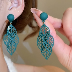Detailed view of dark green matte leaf earrings featuring hollowed-out layered petals