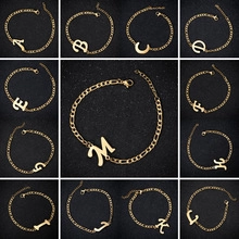 Detail of gold titanium steel Figaro bracelets with uppercase initial pendants A to M