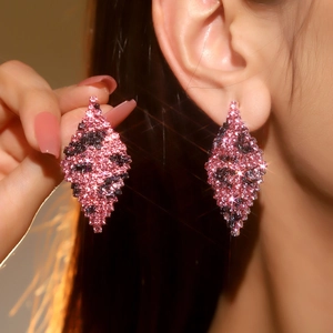 Macro detail of diamond-encrusted geometric rhombus earrings with pink leopard print pattern