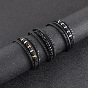 Close-up of multilayer men's braided leather bracelets with metallic cylinder charms