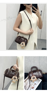 Deep brown Boston bag detail with plush lion charm and adjustable crossbody strap