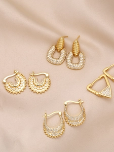 Detailed close-up of gold plated brass earrings set with white zircon on silk
