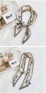 Macro view of beige equestrian silk scarf tied as a bow and laid flat on fabric