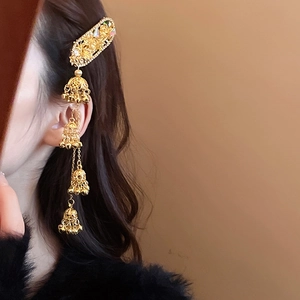Detail of vintage golden ethnic hair clip with floral bells and long tassel fringe