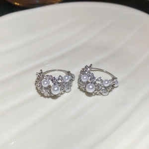 Macro view of silver flower basket earrings with white pearls and sparkling diamonds