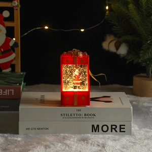 Close-up of a festive red Christmas gift box lantern with Santa Claus and glitter