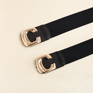 Detail of a wide elastic belt with a golden C-shaped metal buckle and lycra texture