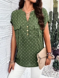 Detail of green V-neck blouse featuring textured Swiss dots and two chest pockets