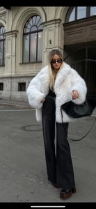 Détail d'un manteau chic en fausse fourrure blanche avec un pantalon noir pour l'hiver