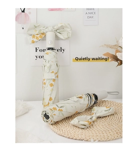 Detail view of cream-colored floral folding umbrellas with elegant ribbon bow accents