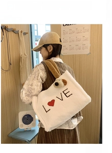 Detailed shot of white plush tote bag with LOVE embroidery and brown puppy plushie charm