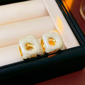 Macro detail of French vintage square cutout earrings with white marble pattern resin