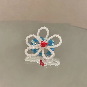 Détail d'une bague en perles faite main en forme de fleur avec reflet sur miroir poli