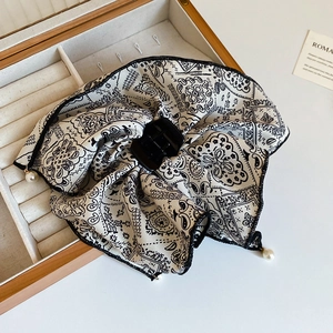 Detail of paisley print bow hair claw clip with pearl charm on a vintage jewelry box