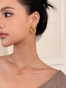 Dettaglio modella che indossa collana a sfera dorata e orecchini a doppio cerchio intrecciati