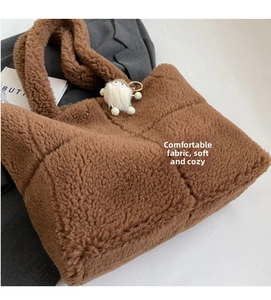 Detail einer gesteppten braunen Teddy-Plüsch-Tasche mit weicher Textur und Anhänger