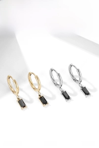 Detail view of gold and silver hoop earrings with rectangular black gemstone pendants