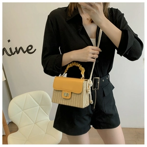 Detail of straw crossbody bag with bright yellow leather pleats and metal twist lock