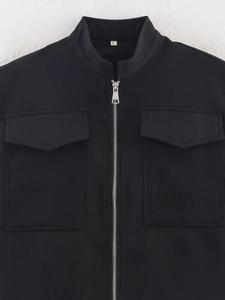 Detail of black sleeveless jacket showing silver zipper and large front utility pockets